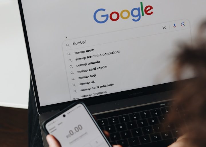 Person nutzt ein Smartphone und einen Laptop mit Google-Suche im Vordergrund bei Namensentwicklung.