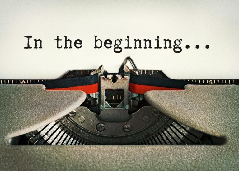 Schreibmaschine mit dem Text "In the beginning..." auf beschriftetem Papier bei Namensentwicklung.