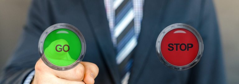 Ein Mann einer Namensagentur im Anzug hält grüne „GO“- und rote „STOP“-Schilder in den Händen.