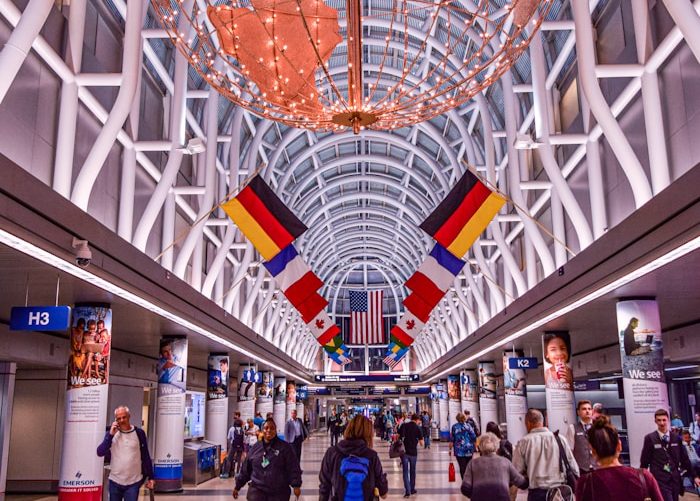 Ein Flughafeninneres mit Flaggen verschiedener Länder und Reisenden bei Namensentwicklung.